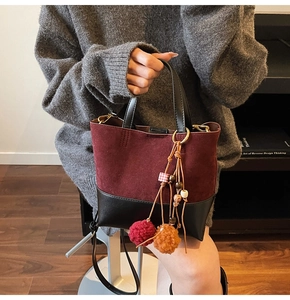 Detail of burgundy suede and black leather handbag with a colorful beaded tassel charm