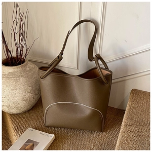 Close-up of olive brown lychee leather texture and white decorative stitching on tote bag