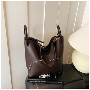 Detail of dark brown lychee grain leather tote bag with white contrast piping on book