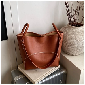 Close-up of brown pebbled leather tote bag with sturdy handles and shoulder strap detail