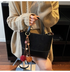 Detail of contrast stitch handbag with faux suede texture and wooden bead charm