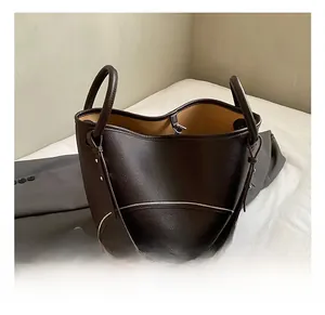 Detailed view of dark brown pebbled leather tote with curved design and silver zippers