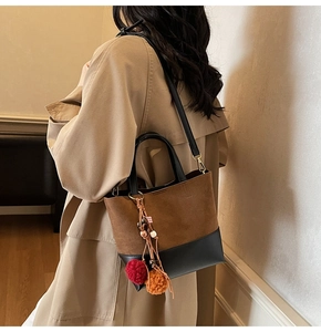 Detail of color-block handbag with brown suede, black leather, and plush charms