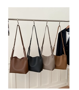 Row of large capacity bucket bags in lychee leather grain with minimalist shoulder straps