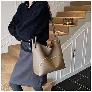 Close-up of taupe leather tote bag with contrast stitching on elegant stairs