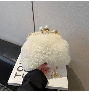 Detailed shot of white plush faux fur handbag with golden pearl clasp and metal chain strap