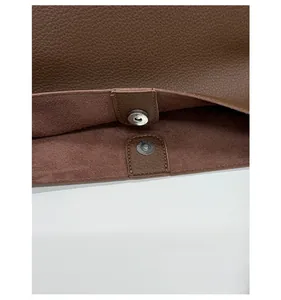 Detail of magnetic snap closure and pebble grain leather on brown bucket bag
