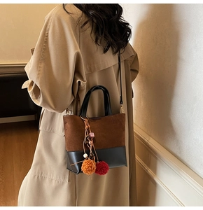 Detail of color-blocked brown and black tote bag worn with a stylish trench coat