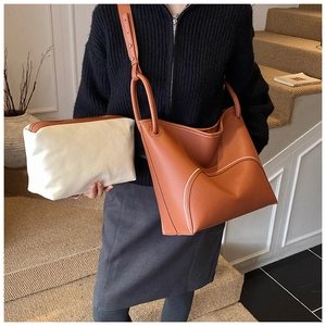 Detail view of brown pebbled leather tote with white zip pouch on stairs