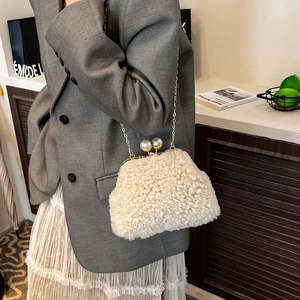 Detail of plush lamb wool clutch bag with gold chain strap and large pearl closure