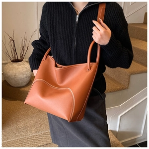 Brown leather tote bag featuring contrast white stitching and spacious interior design