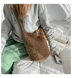Detailed texture view of brown faux fur bucket bag with matching shoulder strap on model