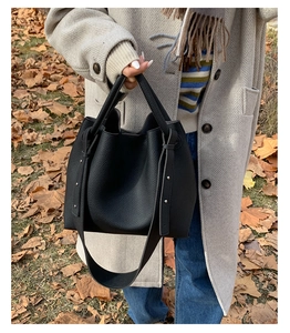 Detail shot of black pebbled leather bucket bag with metallic rivet accents for women