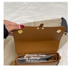 Detail view of the brown leather shoulder bag featuring a secure magnetic buckle closure
