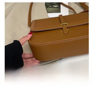 Detail showing the brown matte leather surface and precise stitching on the square handbag