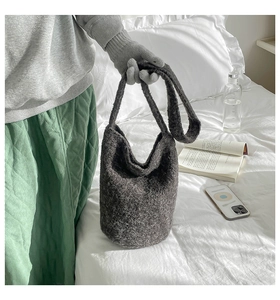 Detail of dark grey plush bucket bag showing soft lamb wool texture and shoulder strap