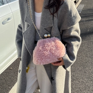 Detailed shot of pink plush crossbody bag with metal chain on a grey coat