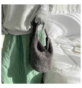 Detailed texture of dark gray plush bucket bag in a cozy lifestyle indoor setting