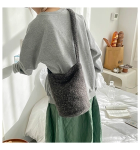 Close-up of charcoal plush bucket bag texture shown on model in cozy home setting
