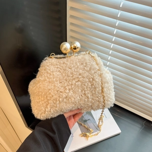 Detail of cream plush shoulder bag featuring large pearl clasps and golden chain strap