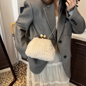 Detail of cream plush chain bag featuring soft faux fur and oversized pearl clasps