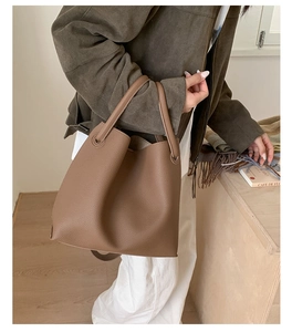 Detail of dark brown lychee textured leather bucket bag held by a model for daily commute