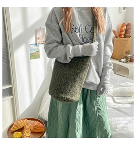 Detail of dark green plush bucket bag paired with autumn winter casual outfit