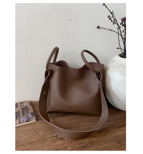 Detail of brown litchi pattern leather bucket bag with wide strap and round handles