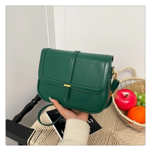 Detail of forest green vintage crossbody bag with metal buckle in a lifestyle setting