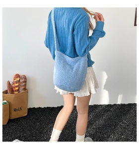 Detail of light blue plush bucket bag with wide shoulder strap on a striped sweater