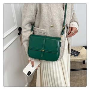 Detailed view of green leather crossbody bag with gold buckle on a stylish model