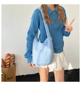 Close-up of light blue plush bucket bag with wide shoulder strap on casual outfit