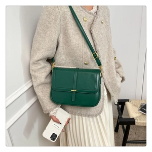 Detail of emerald green leather crossbody bag with champagne gold hardware and strap