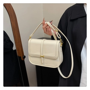 Detail of off-white faux leather square bag with gold magnetic buckle and slim strap