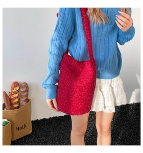 Detail of red plush crossbody bucket bag featuring soft textured faux shearling material
