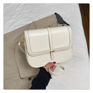 Close-up of beige leather shoulder bag with elegant gold buckle and precise stitching