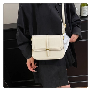 Detail of cream white rectangular shoulder bag featuring gold hardware and slim strap