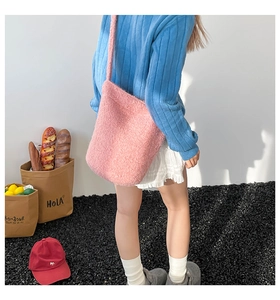 Detailed texture of pink plush shearling bucket bag worn with casual outfit