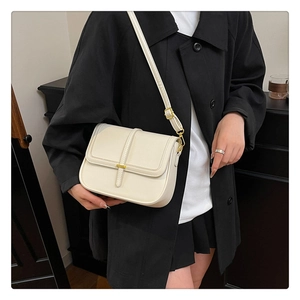 Detail view of cream crossbody bag with gold hardware buckle and vertical leather trim
