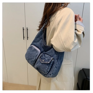 Detail of dark blue washed denim shoulder bag with functional purple zipper and flap pockets