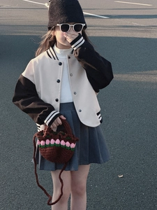 Close-up of a child wearing a knit baseball jacket with a handmade tulip woven handbag