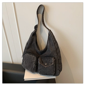 Detailed shot of dark grey denim shoulder bag with vintage stitching and utility pockets