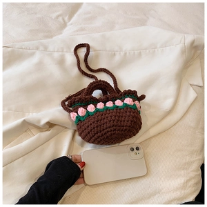 Close-up of brown crochet bucket bag with pink floral accents and woven texture