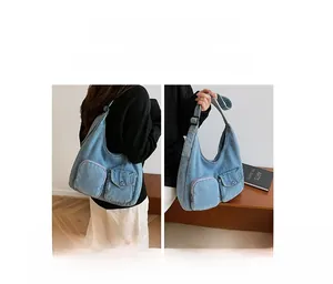 Detail of washed blue denim tote bag featuring dual front buckle pockets and wide shoulder strap