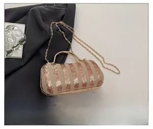Detail view of champagne sequin evening bag with gold handle and chain for size comparison