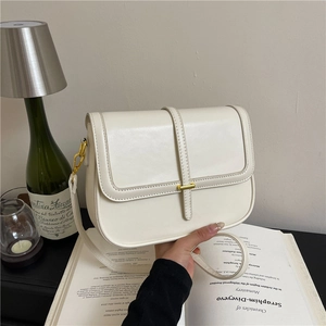 Chic cream white crossbody bag with gold hardware shown in a cozy home setting