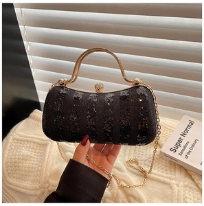 Detail of black sequin evening bag featuring gold metal handle and crystal clasp