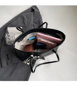 Macro view of a black tote bag showing spacious interior with tablet and phone