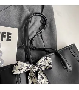 Detail of black tote bag with houndstooth ribbon on a business suit background