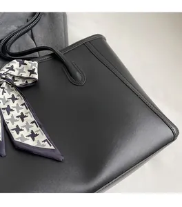 Detail of black matte leather tote bag with V-shaped stitching and houndstooth scarf